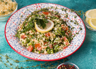Tabule salad of bulgur, tomatoes, spices, dill on a blue background. Traditional oriental cuisine.