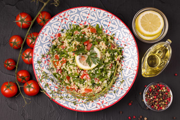 Tabule Salad of bulgur, olive oil, tomato, parsley and spices. on a black background. Eastern cuisine. bulgur dish