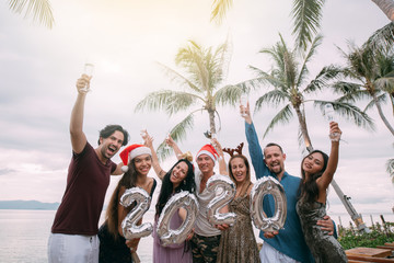 A large company has fun with champagne by the ocean in the tropics.