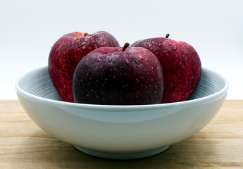 Red apples on wooden table, white background
