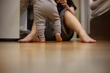 baby walking towards mother. small kid walk on bedroom wooden floor. mother sitting in wait. warm loving family concepts. happy moments of children growing up.