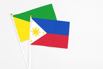 Philippines and French Guiana stick flags on white background. High quality fabric, miniature national flag. Peaceful global concept.White floor for copy space.