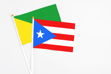 Puerto Rico and French Guiana stick flags on white background. High quality fabric, miniature national flag. Peaceful global concept.White floor for copy space.
