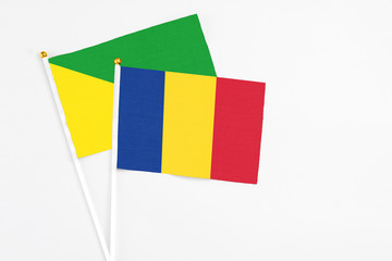 Romania and French Guiana stick flags on white background. High quality fabric, miniature national flag. Peaceful global concept.White floor for copy space.