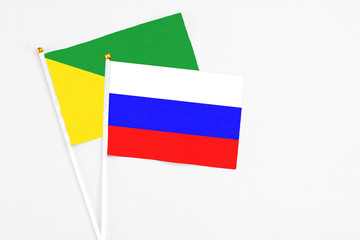 Russia and French Guiana stick flags on white background. High quality fabric, miniature national flag. Peaceful global concept.White floor for copy space.