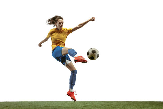 Young female soccer or football player with long hair in sportwear and boots kicking ball for the goal in jump on white background. Concept of healthy lifestyle, professional sport, motion, movement.