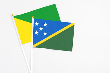 Solomon Islands and French Guiana stick flags on white background. High quality fabric, miniature national flag. Peaceful global concept.White floor for copy space.