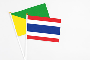 Thailand and French Guiana stick flags on white background. High quality fabric, miniature national flag. Peaceful global concept.White floor for copy space.