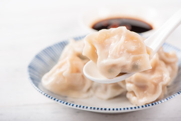 Fresh, delicious boiled pork, shrimp gyoza dumplings on white background with soy sauce and chopsticks, close up, lifestyle. Homemade design concept.