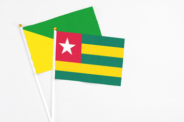 Togo and French Guiana stick flags on white background. High quality fabric, miniature national flag. Peaceful global concept.White floor for copy space.