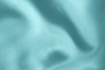Light blue colored Background of soft draped fabric. Beautiful satin silk textured cloth for making clothes and curtains. Elegant textile texture.