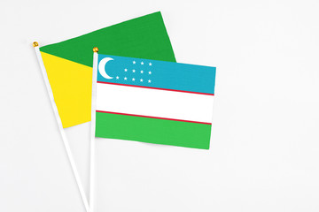 Uzbekistan and French Guiana stick flags on white background. High quality fabric, miniature national flag. Peaceful global concept.White floor for copy space.
