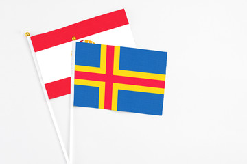 Aland Islands and French Polynesia stick flags on white background. High quality fabric, miniature national flag. Peaceful global concept.White floor for copy space.