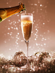 pouring champagne into a champagne glass on a bokeh christmas background © Tjeerd