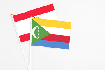 Comoros and French Polynesia stick flags on white background. High quality fabric, miniature national flag. Peaceful global concept.White floor for copy space.