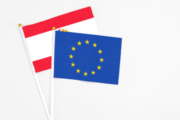 European Union and French Polynesia stick flags on white background. High quality fabric, miniature national flag. Peaceful global concept.White floor for copy space.