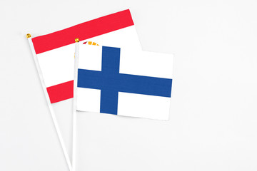 Finland and French Polynesia stick flags on white background. High quality fabric, miniature national flag. Peaceful global concept.White floor for copy space.