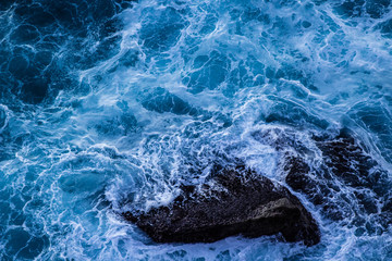 Violent energetic waves crashing on a rock in Sydney Australia. Light and dark blue water foaming whilst waves break to the shore. Deep Sea.