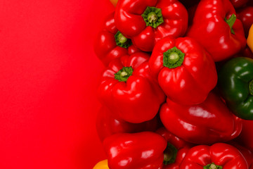 Fresh red, yelow, green bell pepper on a red background.