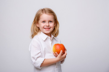 Fototapeta na wymiar portrait of a little blonde girl hold an Apple on a white background