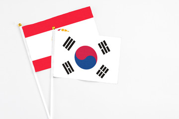 South Korea and French Polynesia stick flags on white background. High quality fabric, miniature national flag. Peaceful global concept.White floor for copy space.