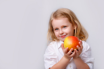 Fototapeta na wymiar portrait of a little blonde girl with an Apple on a white background