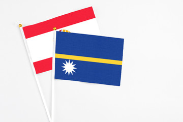 Nauru and French Polynesia stick flags on white background. High quality fabric, miniature national flag. Peaceful global concept.White floor for copy space.