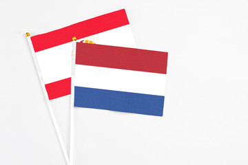 Netherlands and French Polynesia stick flags on white background. High quality fabric, miniature national flag. Peaceful global concept.White floor for copy space.