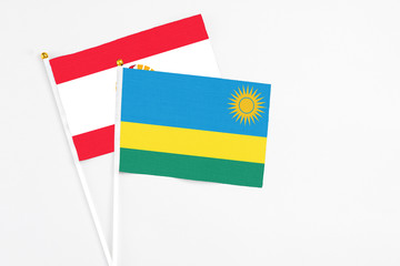 Rwanda and French Polynesia stick flags on white background. High quality fabric, miniature national flag. Peaceful global concept.White floor for copy space.