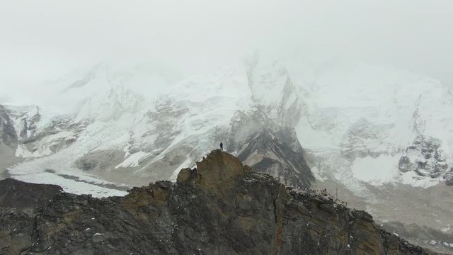 Hiker Man on Top of Kala Patthar Mountain Looking on Khumbu Icefall, Everest and Nuptse. Himalaya, Nepal. Aerial View. Drone Flies Forward
