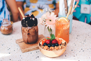 Healthy breakfast bowl with fresh berries, nuts, bananas and chocolate smoothie drink. Vegan food.
