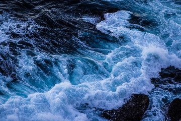 Violent energetic waves crashing on a rock in Sydney Australia. Light and dark blue water foaming whilst waves break to the shore. Deep Sea.