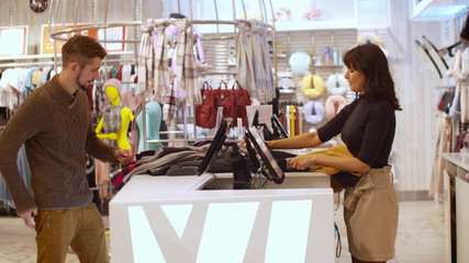 Man buys a lot of clothes in a store