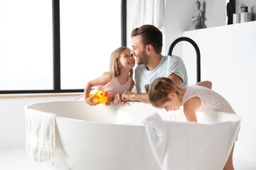 Young father with little daughters in bathroom