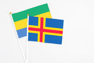 Aland Islands and Gabon stick flags on white background. High quality fabric, miniature national flag. Peaceful global concept.White floor for copy space.