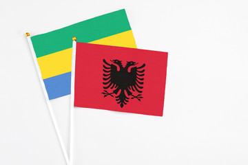 Albania and Gabon stick flags on white background. High quality fabric, miniature national flag....