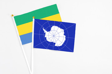 Antarctica and Gabon stick flags on white background. High quality fabric, miniature national flag. Peaceful global concept.White floor for copy space.