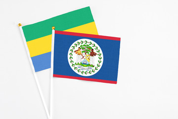 Belize and Gabon stick flags on white background. High quality fabric, miniature national flag. Peaceful global concept.White floor for copy space.