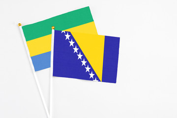 Bosnia Herzegovina and Gabon stick flags on white background. High quality fabric, miniature...