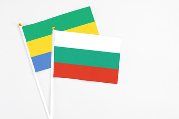 Bulgaria and Gabon stick flags on white background. High quality fabric, miniature national flag. Peaceful global concept.White floor for copy space.