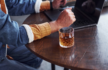 Close up view of senior in fashionable clothes that works with laptop