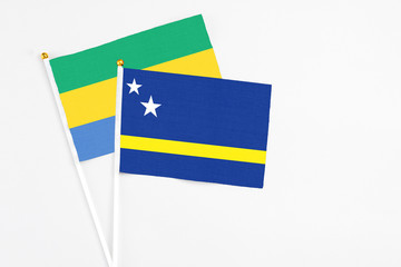 Curacao and Gabon stick flags on white background. High quality fabric, miniature national flag. Peaceful global concept.White floor for copy space.