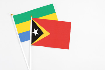 East Timor and Gabon stick flags on white background. High quality fabric, miniature national flag....