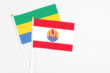 French Polynesia and Gabon stick flags on white background. High quality fabric, miniature national flag. Peaceful global concept.White floor for copy space.