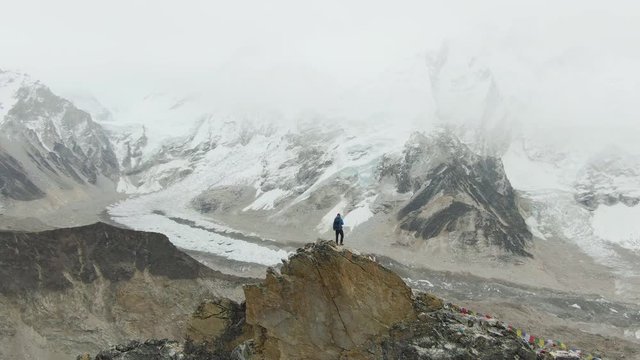 Hiker Man on Top of Kalapatthar Mountain. Khumbu Icefall, Everest Basecamp, Nuptse and Pumori Mountains. Himalaya, Nepal. Aerial View. Drone is Orbiting