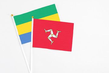 Isle Of Man and Gabon stick flags on white background. High quality fabric, miniature national flag. Peaceful global concept.White floor for copy space.