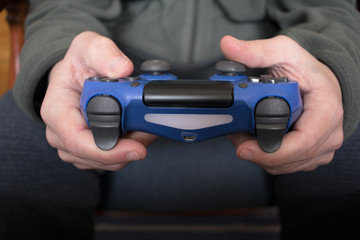 Boy hands holding a blue gamepad playing video games