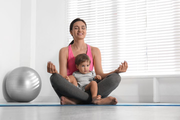 Obraz premium Young woman meditating with her son at home