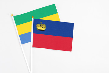 Liechtenstein and Gabon stick flags on white background. High quality fabric, miniature national flag. Peaceful global concept.White floor for copy space.