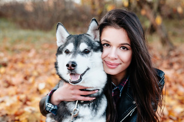 Happy woman hugging her dog in autumn park. Friendship between human and animal